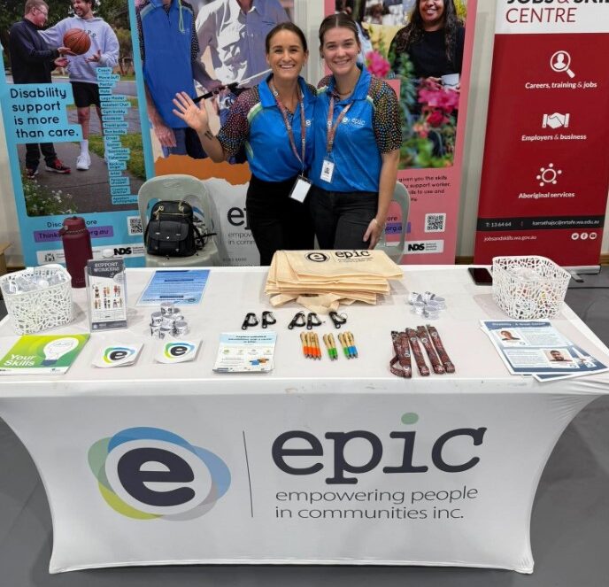 Two EPIC workers smiling at a stall